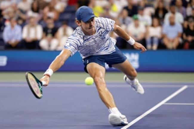 Alex de Minaur stretches to reach a ball against Dan Evans.