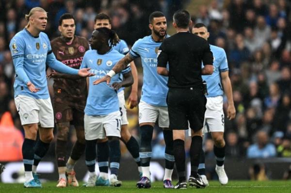 Manchester City players surround Michael Oliver