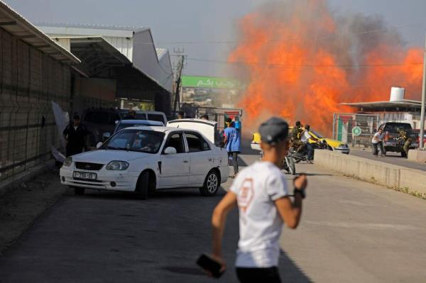 Palestinians and militants from the Ezzedine al-Qassam Brigades run towards the Erez crossing between Israel and the northern Gaza Strip.