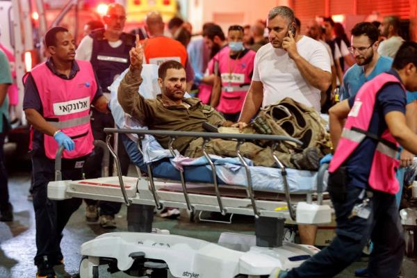 An injured Israeli officer gestures as he arrives at a hospital, following the mass-infiltration.