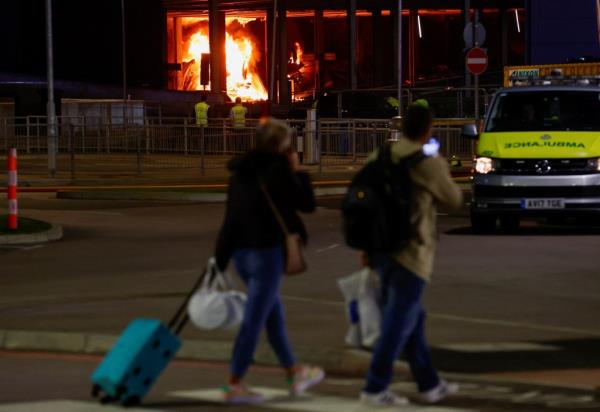People leave as emergency services respond to a fire in Terminal Car Park 2 at London Luton airport in Luton, Britain, on Wednesday.
