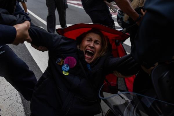 A pro-Palestinian demonstrator is arrested while sitting in a foldable chair placed in the middle of the road on October 7, 2024 in New York City.
