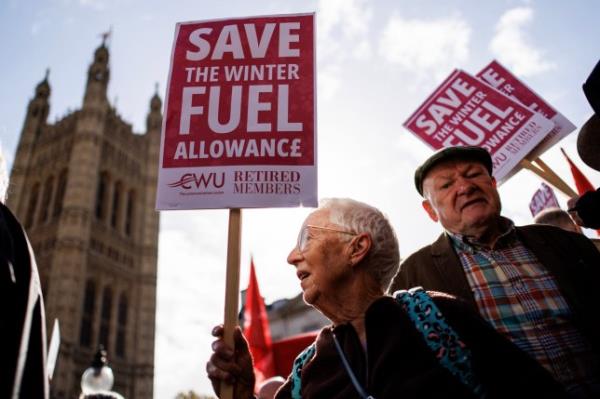 Protesters hold placards while campaigning for the reversal of the winter fuel payment cuts to pensioners, which is proposed by the British government, at Old Palace Yard, in London