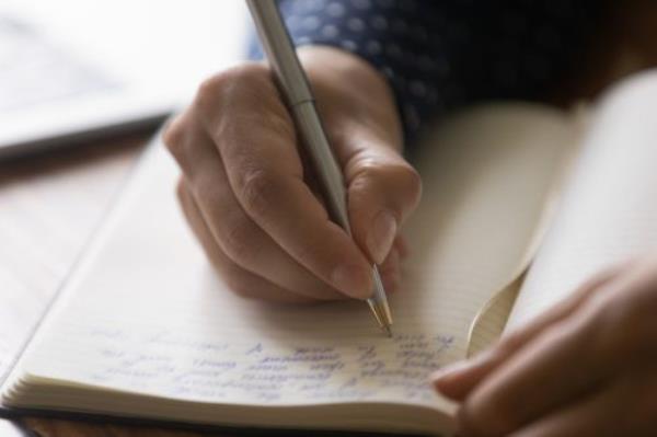 Hands writing in a journal.