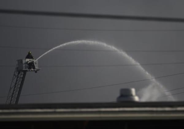 person stands on aerial lift as it sprays liquid down