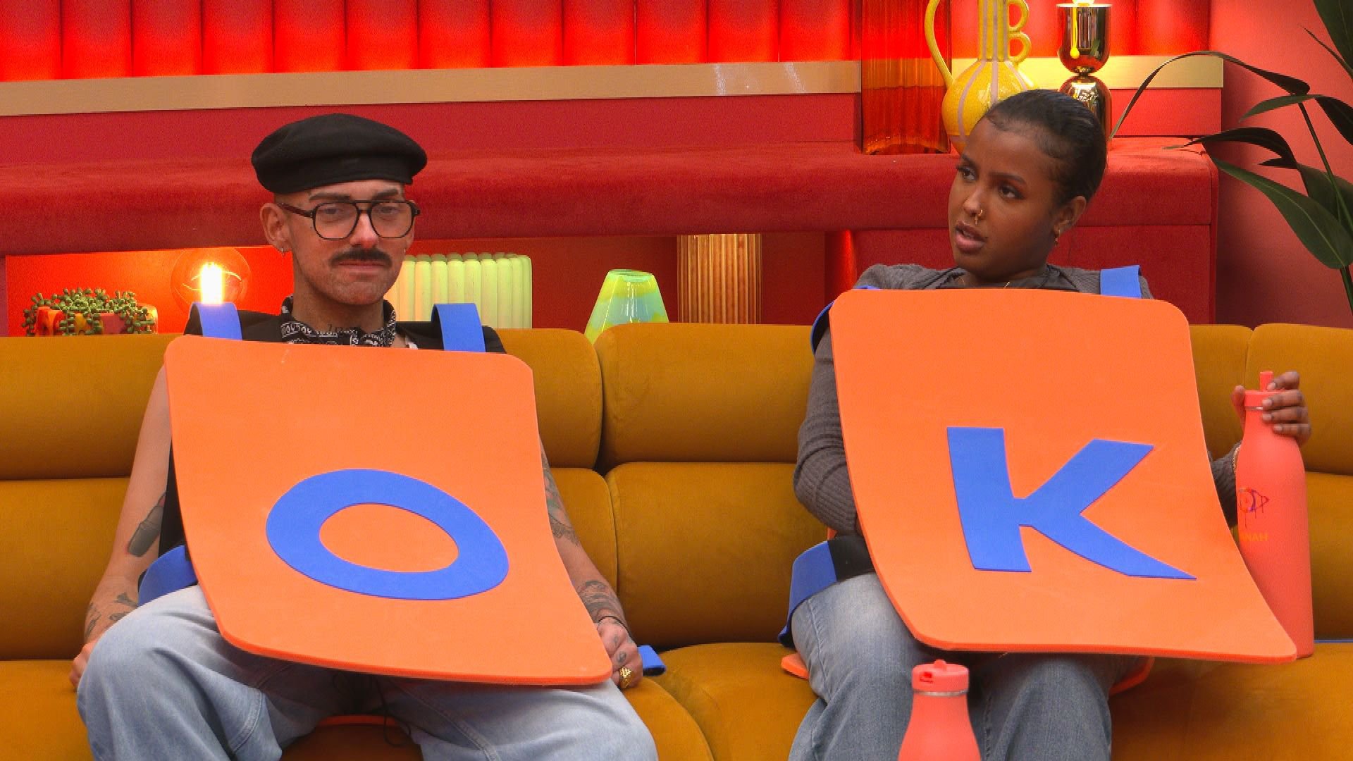 Dean and Hanah (R) sit together on sofa dressed as letters O and K during episode of Big Brother