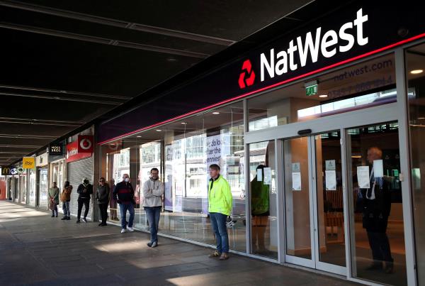 People maintain social distance while they queue outside a Natwest bank