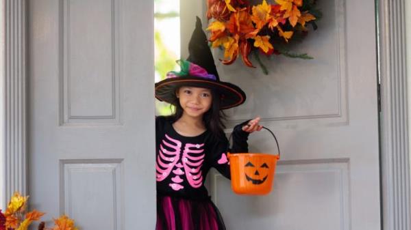 little girl in witch hat going trick or treating on halloween