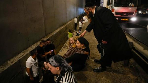 People take cover on the side of a road as a siren sounds a warning of incoming missiles on a freeway in Shoresh, Israel Tuesday, Oct. 1, 2024. (AP Photo/Ohad Zwigenberg)