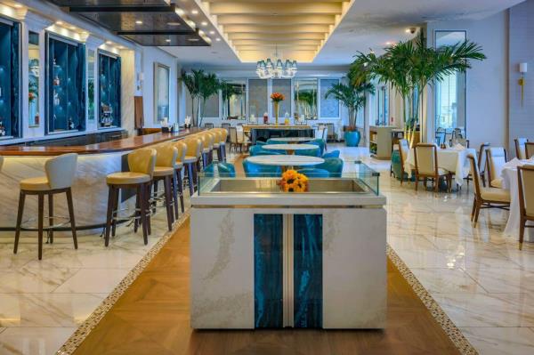 Renovated interior of Polpo restaurant with tables and chairs at Eau Palm Beach Resort, a property purchased and updated by The Lewis Group.