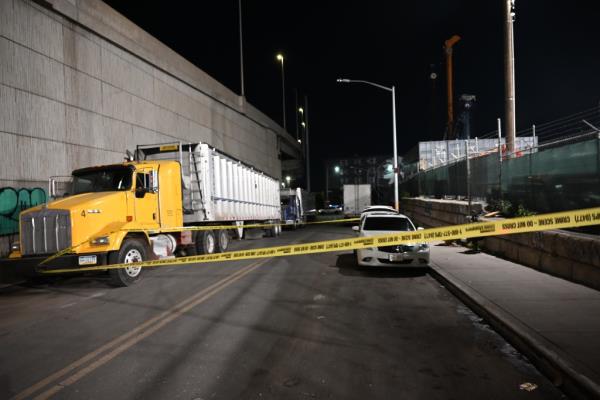 Yellow police tape cordons off tge crime scene on Stewart Avenue and Cherry Street in Greenpoint, where a large semi-trailer and a white SUV are parked.
