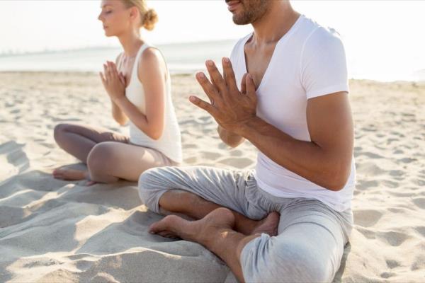 Couple meditating on the beach in the morning