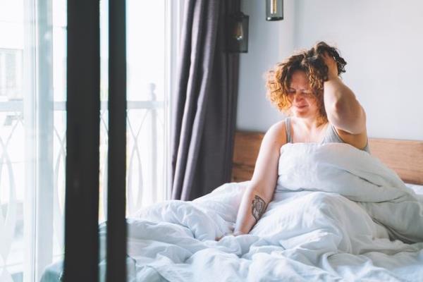 A woman sat up in bed with a hangover