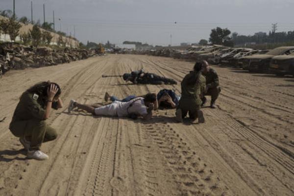 Members of Israeli forces and journalists take cover as a siren warns of incoming rockets fired from the Gaza Strip in an area where hundreds of burned and destroyed vehicles are placed. Picture: AP Photo/Leo Correa Members of Israeli forces and journalists take cover as a siren warns of incoming rockets fired from the Gaza Strip in an area where hundreds of burned and destroyed vehicles are placed. Picture: AP Photo/Leo Correa