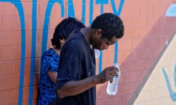 a man pours water on head and  stands next to a women outside 