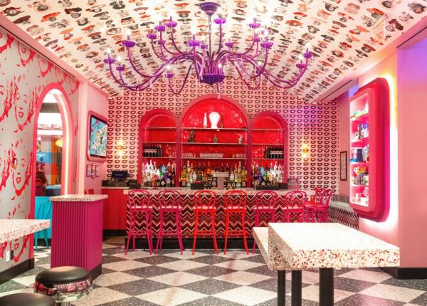 A pink and white themed bar at Serendipity 3 Times Square, featuring a chandelier and chairs.