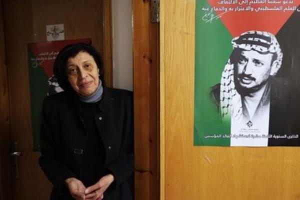 Haifaa Qudsia, a 68-year-old Fatah activist, next to a poster with the image of Yasser Arafat.