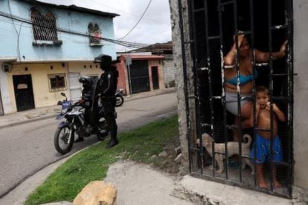 Guayaquil residents look on while police set up a roadblock on Friday.