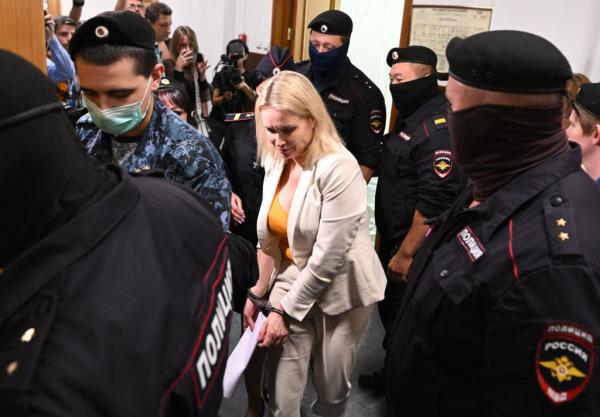 In this file photo taken on August 11, 2022 Marina Ovsyannikova (C), a journalist who became known internationally after protesting against the Russian military action in Ukraine during a prime-time news broadcast on state television, is escorted by police before a court session over charges of "discrediting" the Russian army, in Moscow