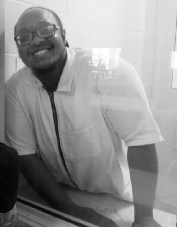 man wearing white collared shirt smiles in black and white photo