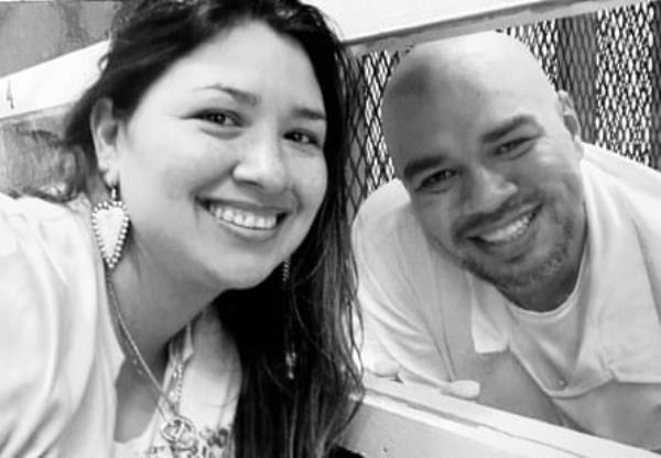 black-and-white selfie of a woman and man smiling as they crouch down on opposite sides of a window separating them