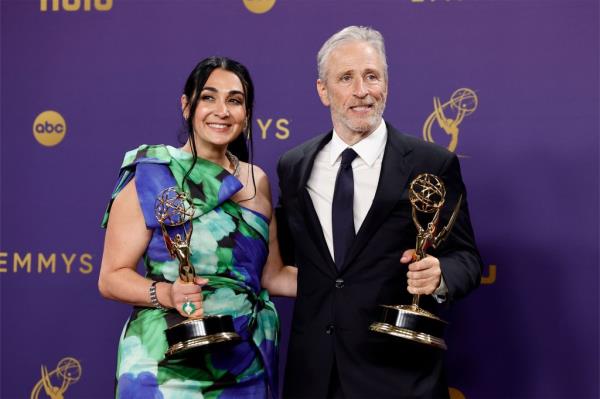 Jon Stewart and a woman holding trophies on 'The Daily Show'