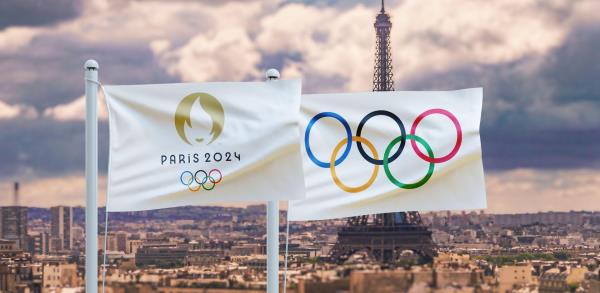 The Olympic flag flying against a backdrop of urban Paris and the Eiffel Tower.