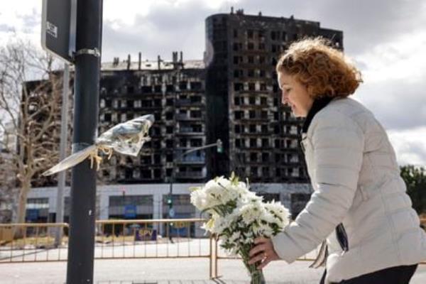A woman leaves a bouquet of flowers on Saturday in memory of the victims of the fire in a building in the Campanar neighborhood of Valencia that claimed the lives of at least 10 people.