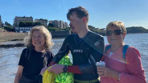Family photo Harrison in a wetsuit with two women