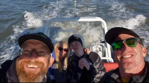 Family Photo Four people on a speed boat, two men in the foreground with Harrison and a woman to the rear