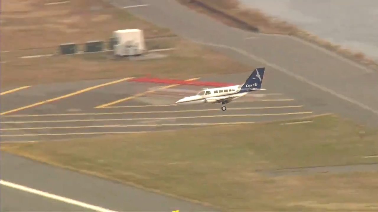 A Cessna 402C approaches Runway 22 at Boston Logan International Airport with grassy patches and the tarmac visible