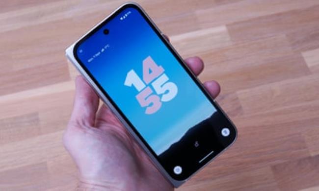 The Google Pixel 9 Pro Fold held in a hand showing the lockscreen while the phone is shut.