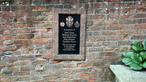 Adrian Harms/ BBC A bronze plaque commemorating those who died is set into the wall of Quakers acre on North Street in Guildford