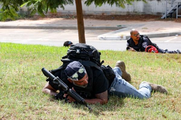 Members of the Israeli security forces take cover during a rocket attack from the Gaza Strip, in the southern city of Sderot on October 8, 2023.