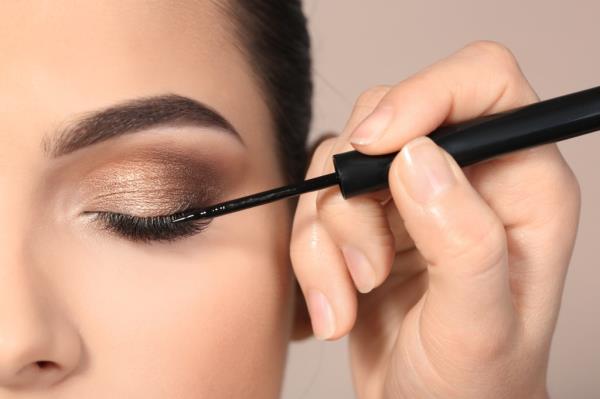 Woman applying eyeliner on top of eyeshadow