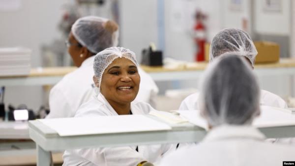 FILE - Women interact at their solar panel factory called Ener-G-Africa, where they produce high-quality solar panels made by an all-female team, in Cape Town, South Africa, Feb. 9, 2023.