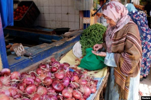 FILE - A woman counts Moroccan currency at a vegetable market in Casablanca, Morocco, June 29, 2017.