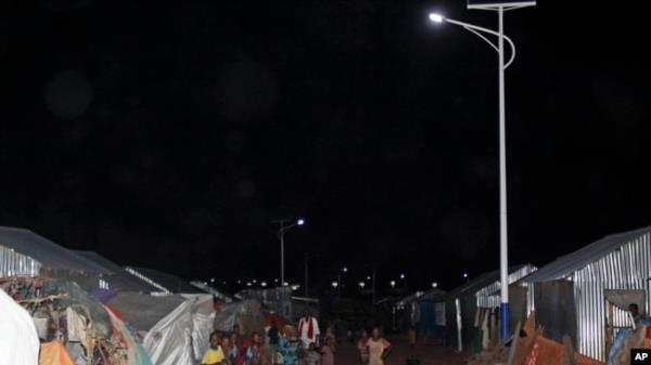 FILE - Children play under the solar powered street lights at a refugee camp in Mogadishu, July 11, 2013.