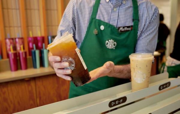 A Starbucks Barista holding a drinks order