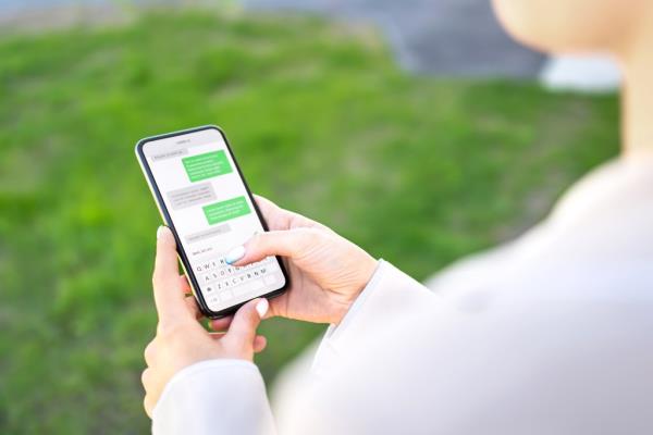 Woman using her smartphone to text in a park during summer