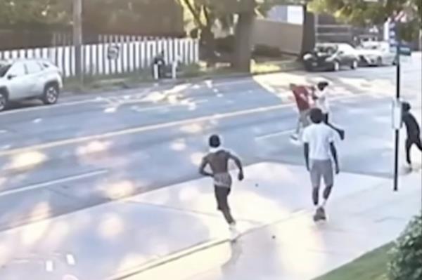 其中一名青少年从后面冲上来,该男子跳入繁忙的街道中以躲避,而其他人则追着他穿过马路。