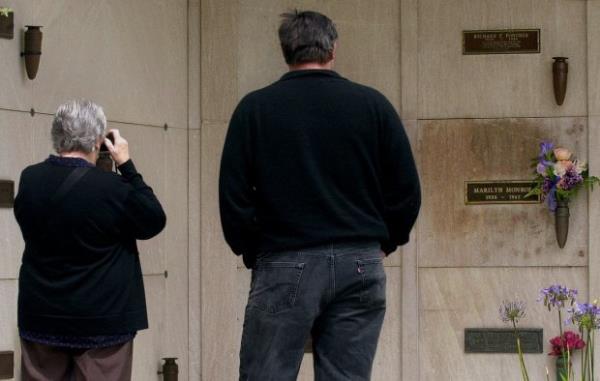 In this April 20, 2001 file photo, Robyn Lowndes from Newcastle, Australia, takes a photo of the crypt of movie star Marilyn Monroe while on a visit with her second cousin George Agnew of Los Angeles to Westwood Village Memorial Park Cemetery in Los Angeles' Westwood district. (AP Photo/Reed Saxon, file)