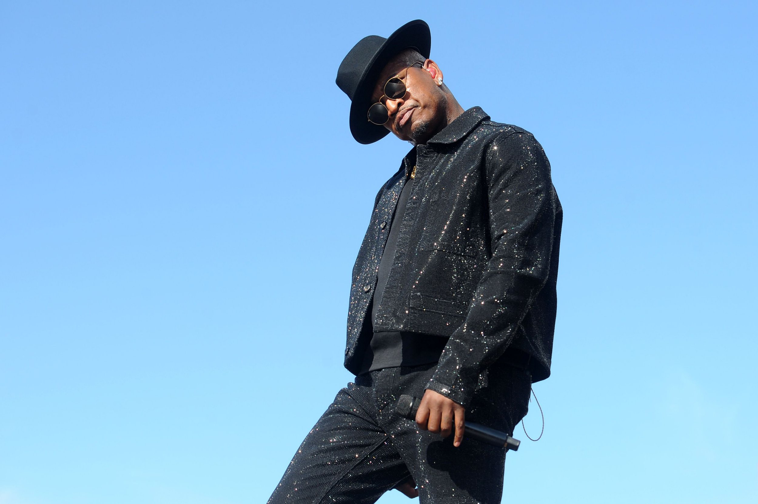 Ne yo dances on stage with blue background behind him