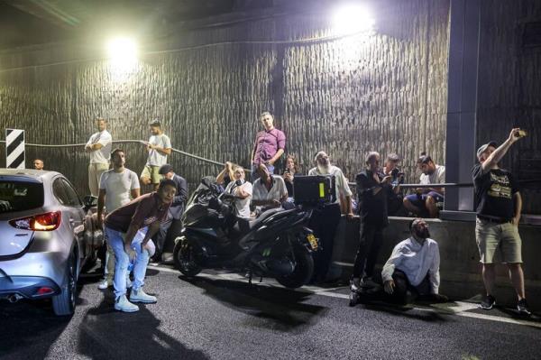 People take cover under a bridge along the side of a highway in Tel Aviv on October 1, 2024. 