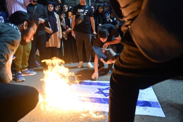 People burning an Israeli flag