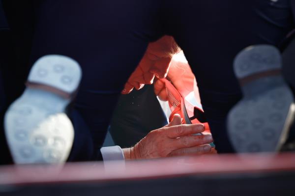 Secret Service agents assisting former President Donald Trump on stage at a campaign rally in Butler, Pennsylvania after he was grazed by a bullet