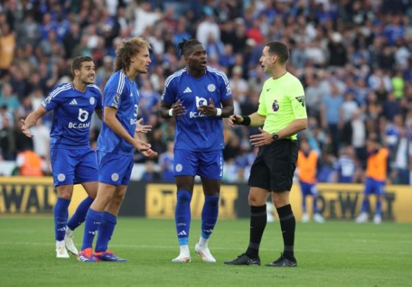 Referee David Coote reacts to Leicester City's Wout Faes (left) and Caleb Okoli during the Premier League match between Leicester City FC and Aston Villa FC