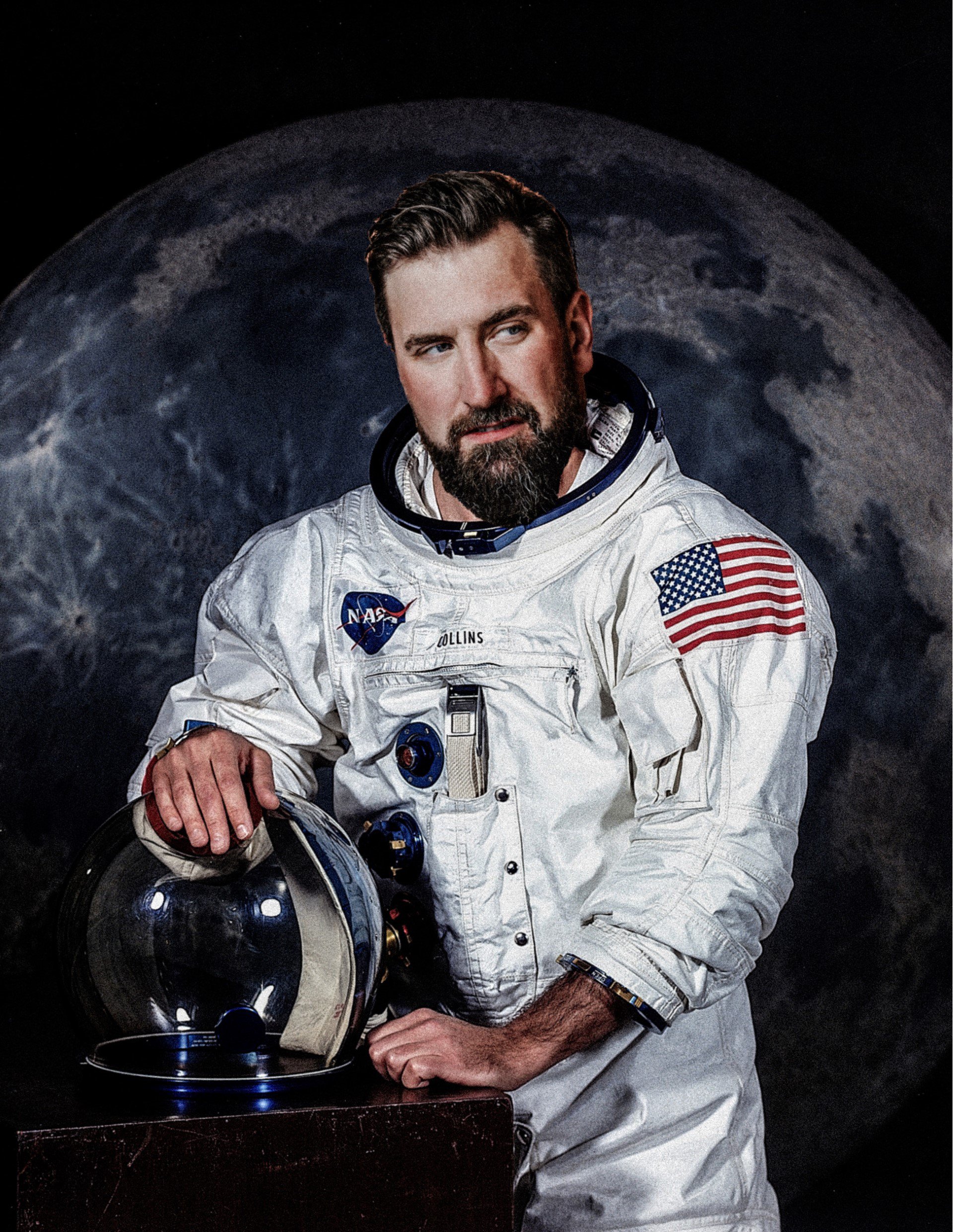 Garrett Millerick in a NASA spacesuit holding a helmet and posing in front of a moon background 