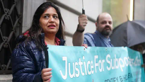 Getty Images Sub-postmaster Seema Misra protesting with a blue banner