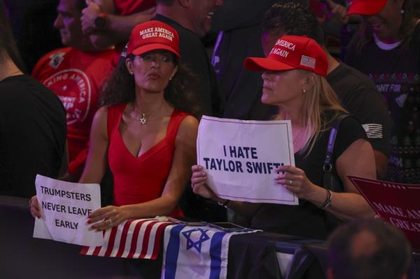 People in the crowd hold signs about Taylor Swift and rally goers leaving early before former US President and Republican nominee for President Donald Trump arrives to a rally at the Nassau Veterans Memorial Coliseum in Uniondale, New York, USA, 18 September 2024.